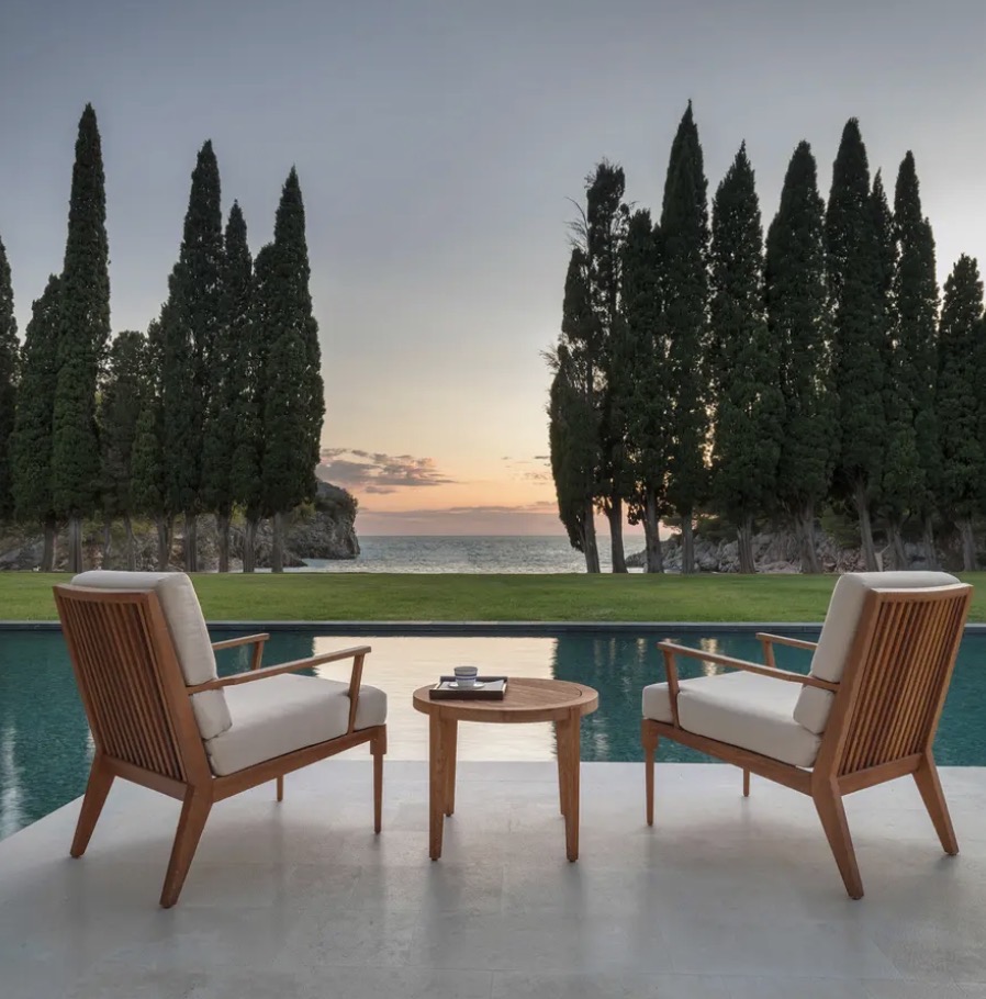 Two chairs at a pool between cypress trees at sunrise